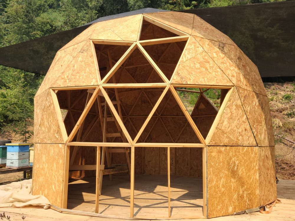 Interior del domo geodésico sin terminar, con la estructura de madera a la vista